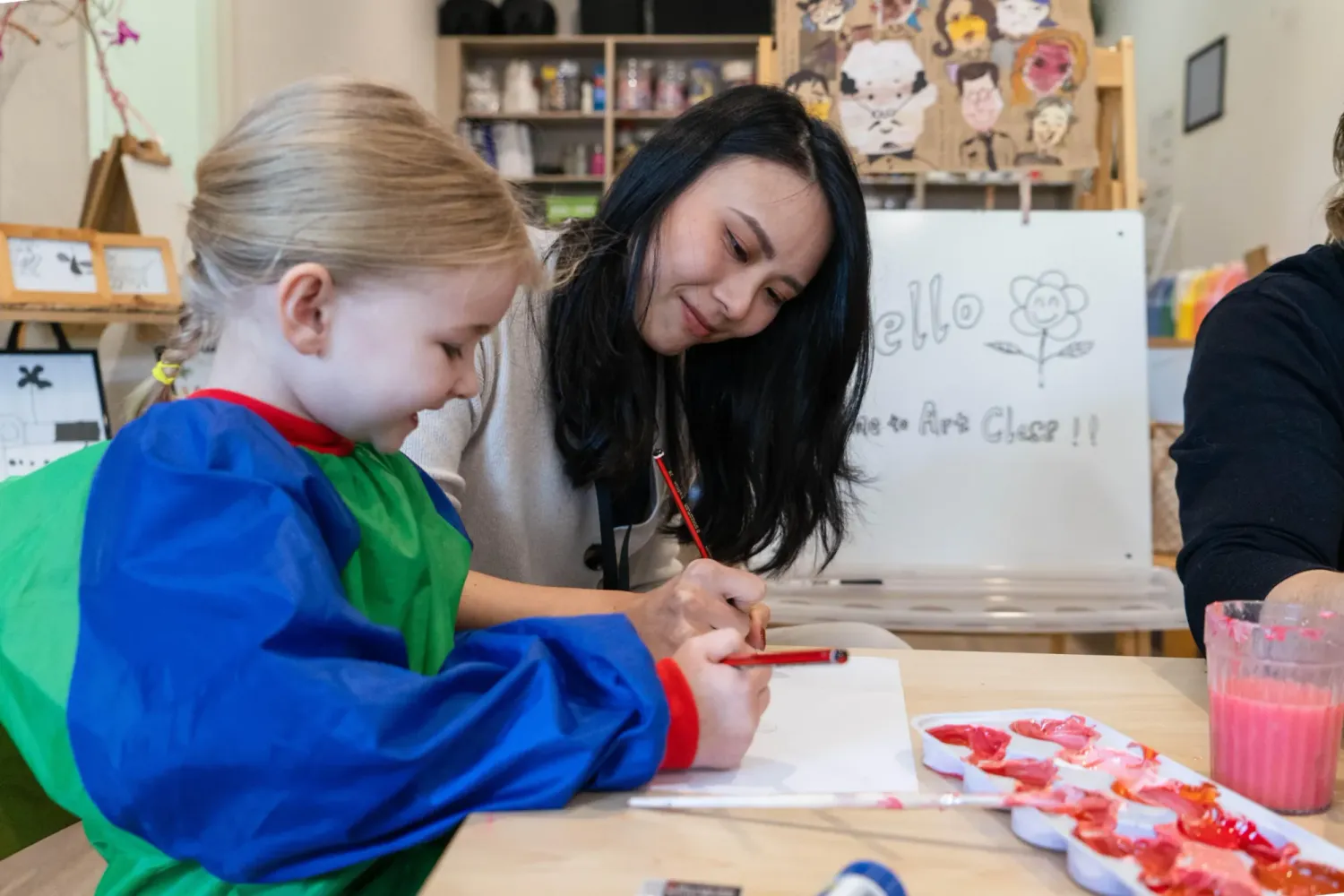 Kayan Lai helping a young student draw in a kids art class