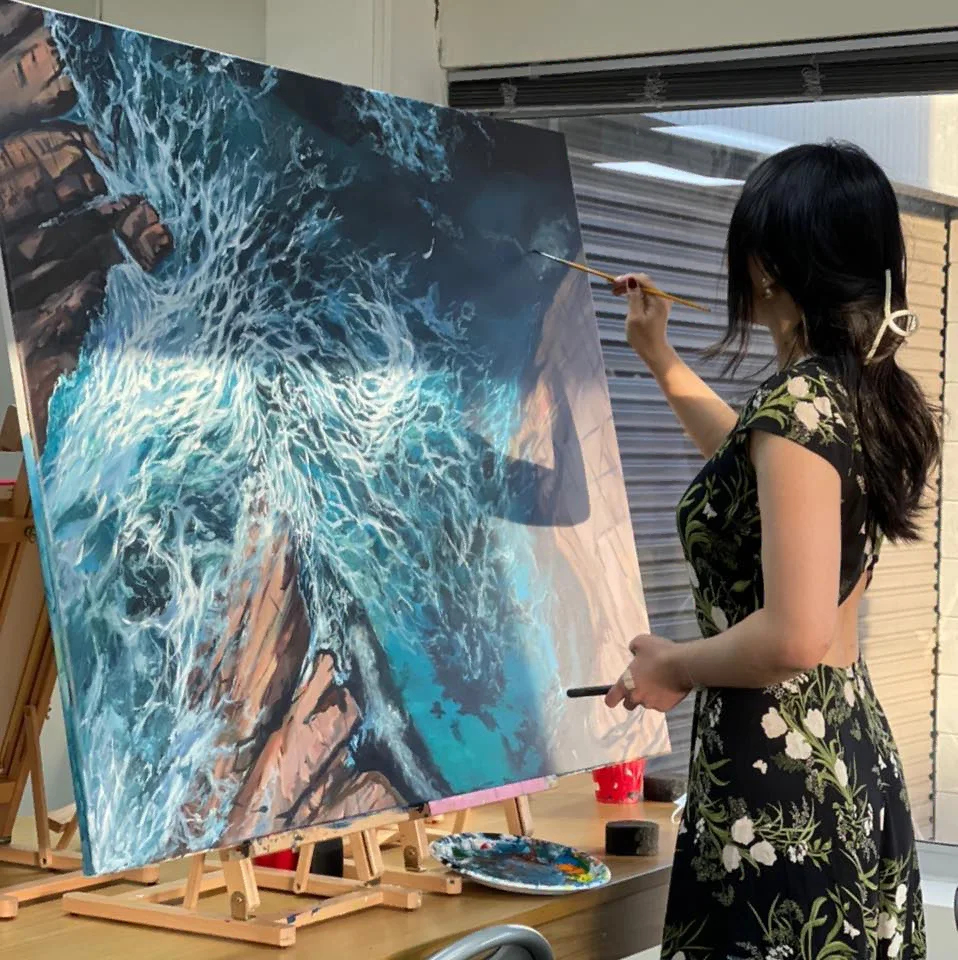 Kayan Lai painting a large seascape canvas at her easel